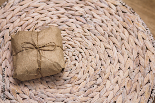 Parcel wrapping in brown craft paper and tie hemp string. Package. Delivery service. Online shopping. Your purchase. Gift box on a table. Decorative wood background. 