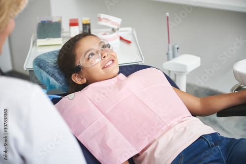 Joyful little girl visiting her professional dentist