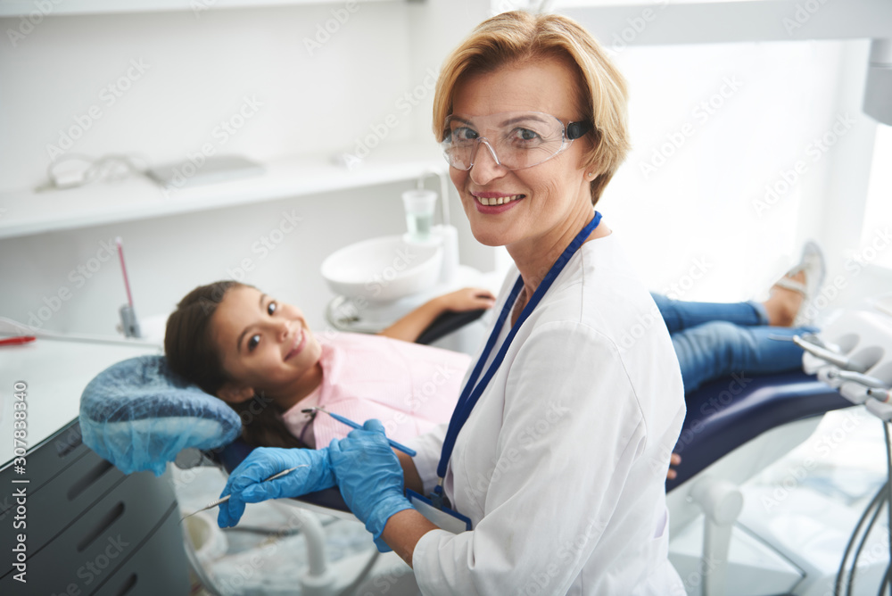 Waist up of a delighted smiling dentist involved in work
