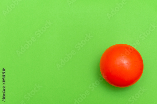 Red Ball hockey ball on a solid bright green flat lay background symbolizing sports and activity with copy space.