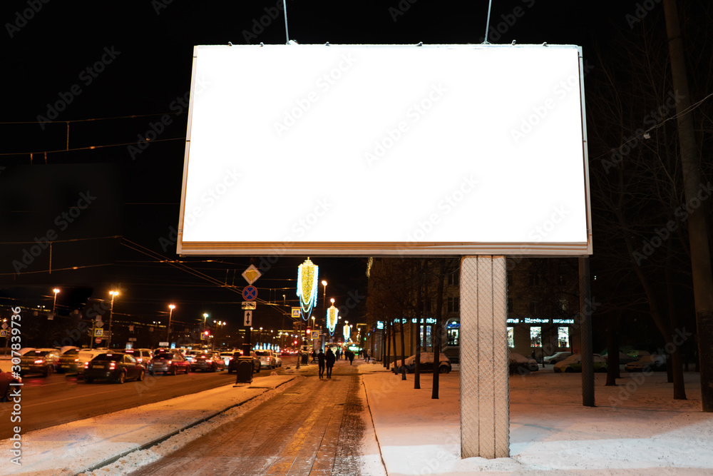 Naklejka premium advertising billboard in the city at night in winter. Ad design mockup with white field. near the road