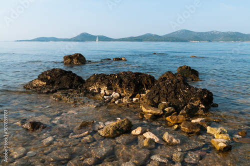 Rocky coast with a view of Adriatic Sea and island and boat from Biograd of Croatia, Europe.