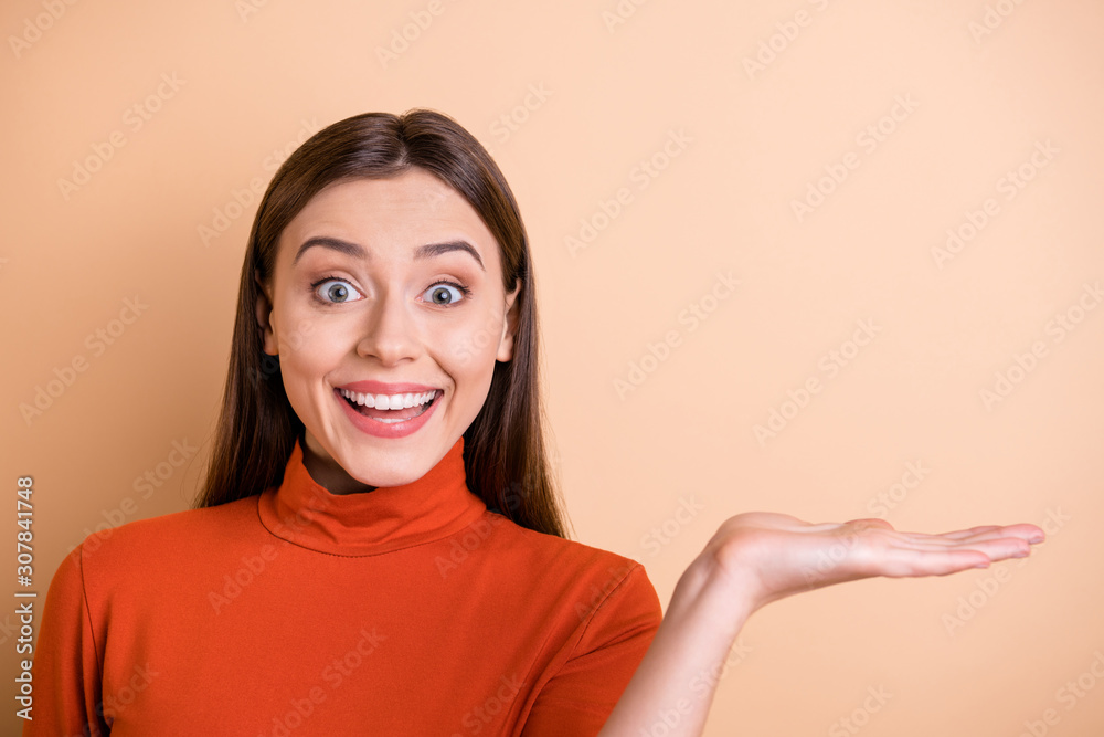Close up photo of white cheerful attractive cute girlfriend showing you something in her hand wearing red turtleneck isolated beige color pastel background Close up photo of white cheerful attractive cute girlfriend showing you something in her hand wearing red turtleneck isolated beige color pastel background