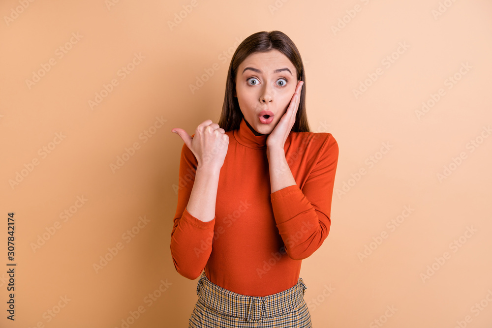 Photo of shocked amazed confused trainee showing something away from her wearing red turtleneck isolated with beige color pastel background Photo of shocked amazed confused trainee showing something away from her wearing red turtleneck isolated with beige color pastel background