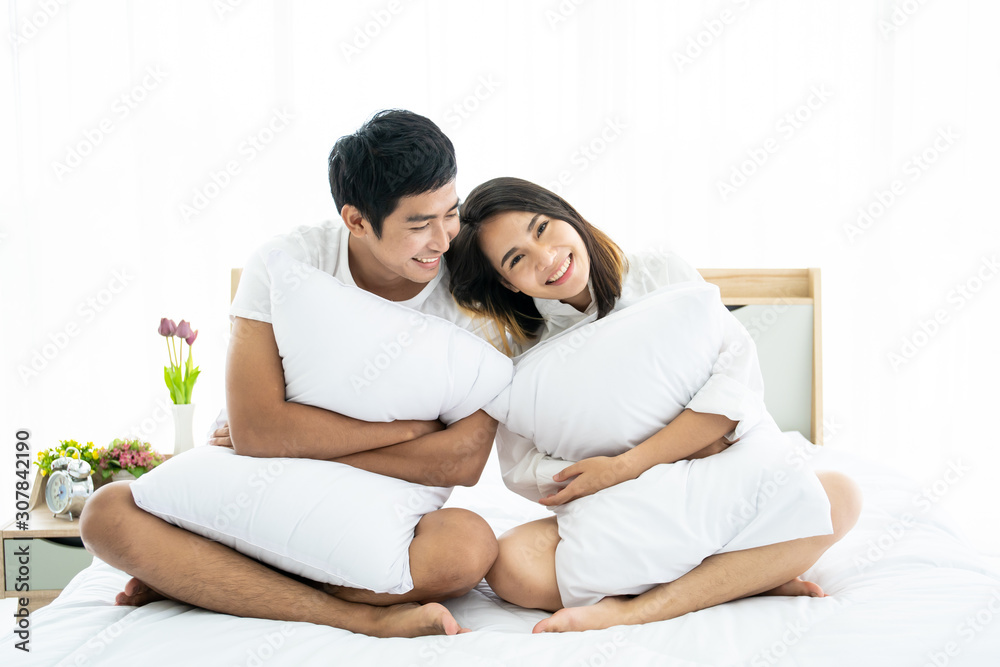 Funny and romantic Asian couple' portrait in bedroom with natural light from window, concept of relationship between husband and wife and being a family. Funny and romantic Asian couple' portrait in bedroom with natural light from window, concept of relationship between husband and wife and being a family.