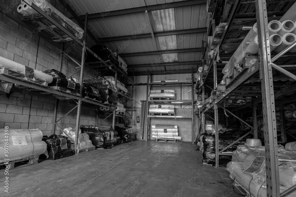 London,England, 28/1/19 Black and white image of the inside huge warehouse factory with shelfs stacked high with tubes and material up to the ceiling of the metal industrial building and large space