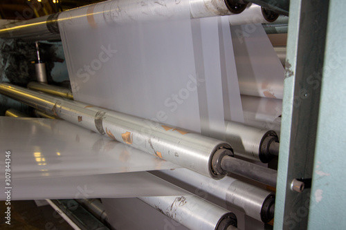 imagery White spool of plastic packaging sheet heavy duty for industrial use outdoors. wrapped around a metal pole ready to feed into a machine for cutting into shape or printing logos.
