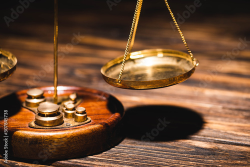 close up view of golden scales of justice on wooden table on black background
