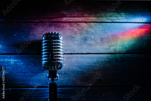 Retro microphone on wooden background and color lights with copy space for text. Horizontal