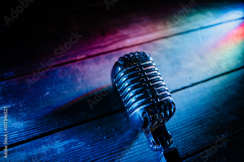 Retro microphone on wooden background and color lights with copy space for text