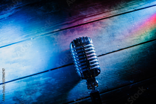 Retro microphone on wooden background and color lights with copy space for text