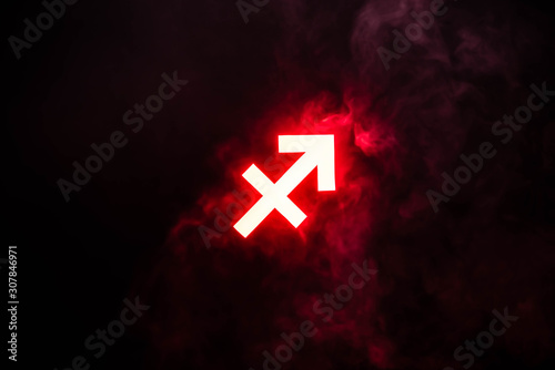 red illuminated Sagittarius zodiac sign with smoke on background photo