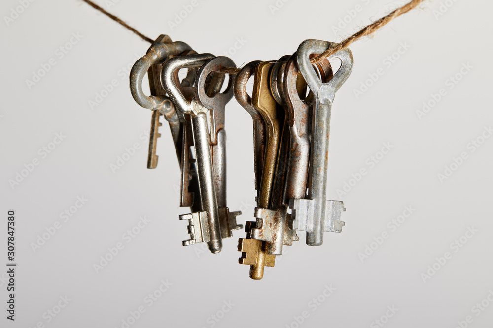 vintage rusty keys hanging on rope isolated on white