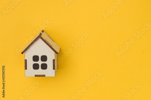 the concept of renting real estate, house toy on a yellow background view from above, of the IOC up and save space