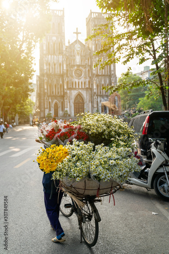 Flower vendor on Hanoi street at early morning with St. Joseph Cathedral church on background photo