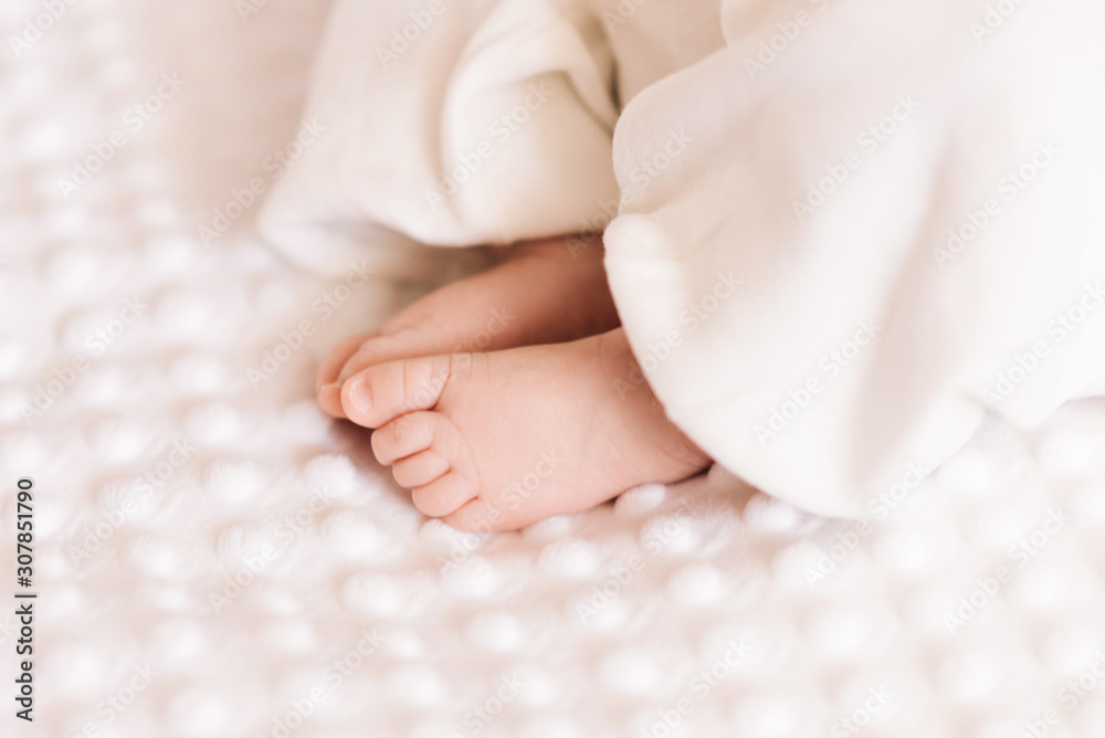 Close up of tiny adorable bare pink baby feet as the infant sleeps on white blanket Close up of tiny adorable bare pink baby feet as the infant sleeps on white blanket