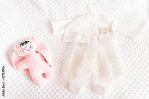 Cute baby dress on light background for christening girl and toy nearby