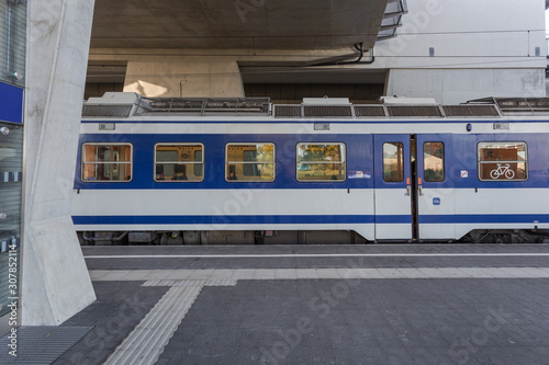 Blue and white train waiting on passengers at an outdoor train stop