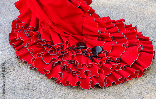 Colorful gipsy flamenco dress isolated on pavement. Flamenco dress of street artist closeup, part of the costume