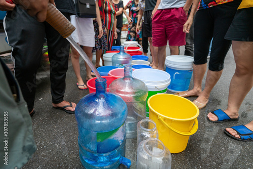 Foto Empty water buckets waiting for fresh water from emergency mobile tank truck