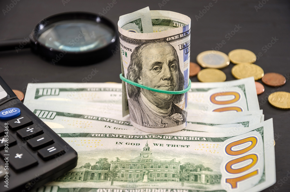 Fototapeta premium dollars, coins and calculator on a black, wooden background. Business concept.