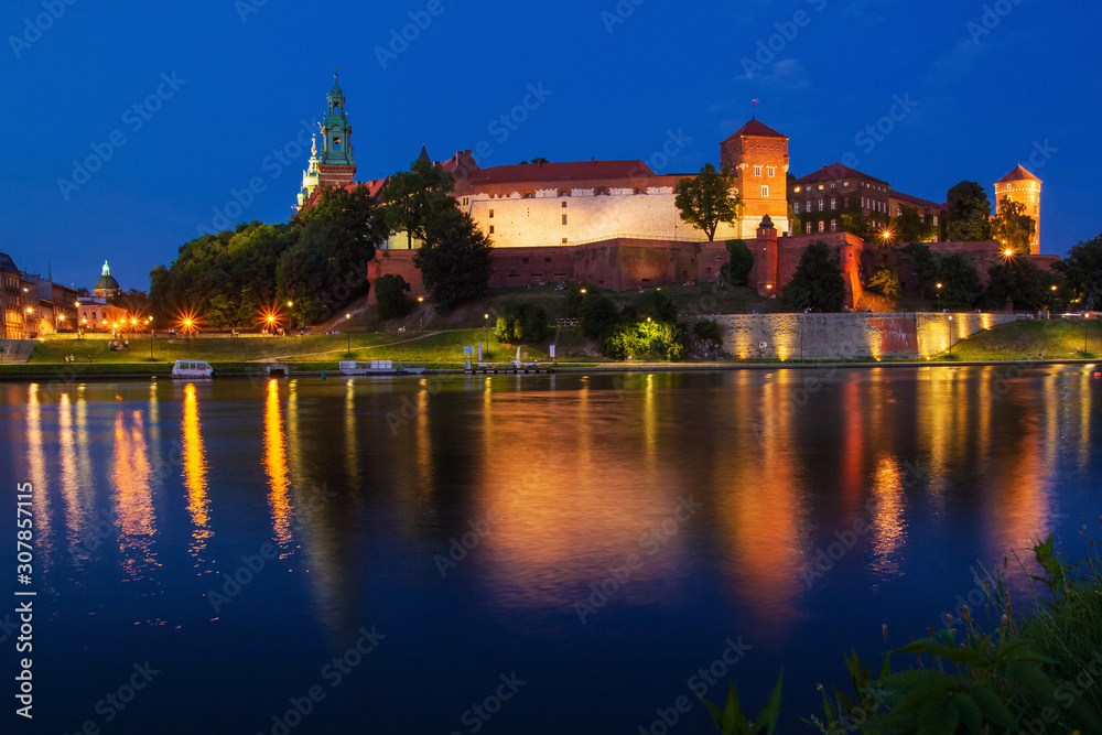 Fototapeta premium Illuminated Wawel Royal Castle in the evening. Beautiful reflection in the Wisla river. Krakow, Lesser Poland, Poland.