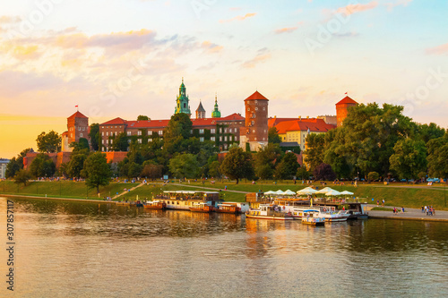Panoramic view of the Wawel Royal Castle in the sunset. Cruise boats on the Wisla river. Krakow, Poland.