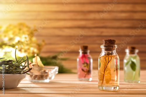 Jars with plant and essence inside on table wooden background