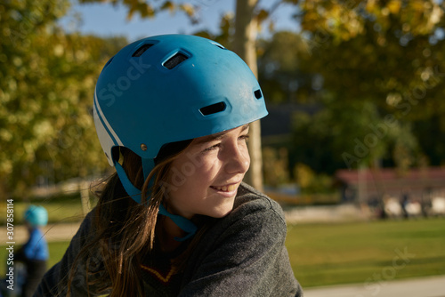 Smiling girl with blue safety bicycle helmet and background of urban landscape and nature © Sergio