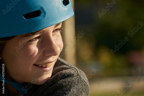 Smiling girl with blue safety bicycle helmet and background of urban landscape and nature © Sergio