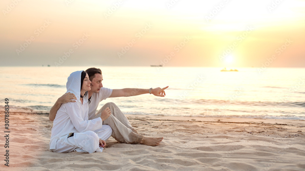 Young couple in love, Attractive man and woman enjoying romantic evening on the beach watching the sunset