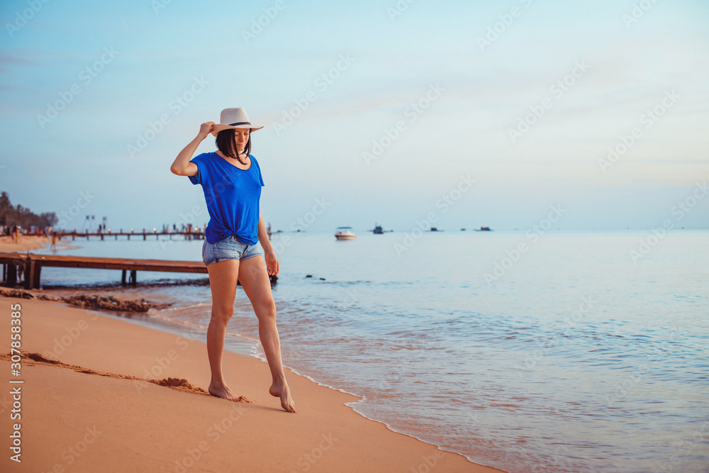 Young woman in hat standing on sand and dreaming.