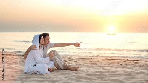 Young couple in love, Attractive man and woman enjoying romantic evening on the beach watching the sunset