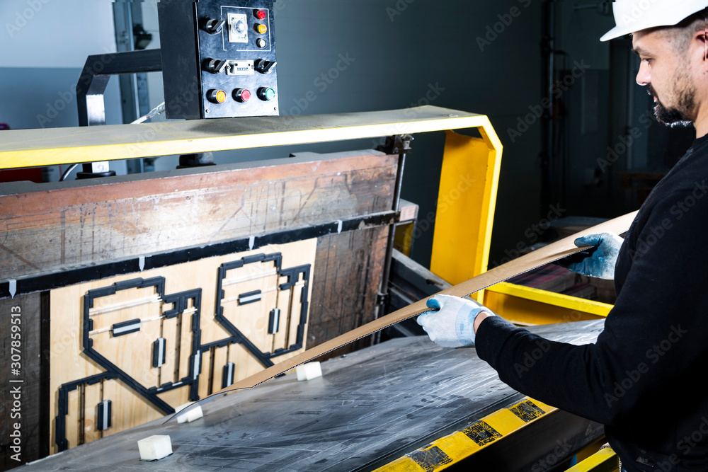 Paper die cutting machine operator during the work. Placing a carton in