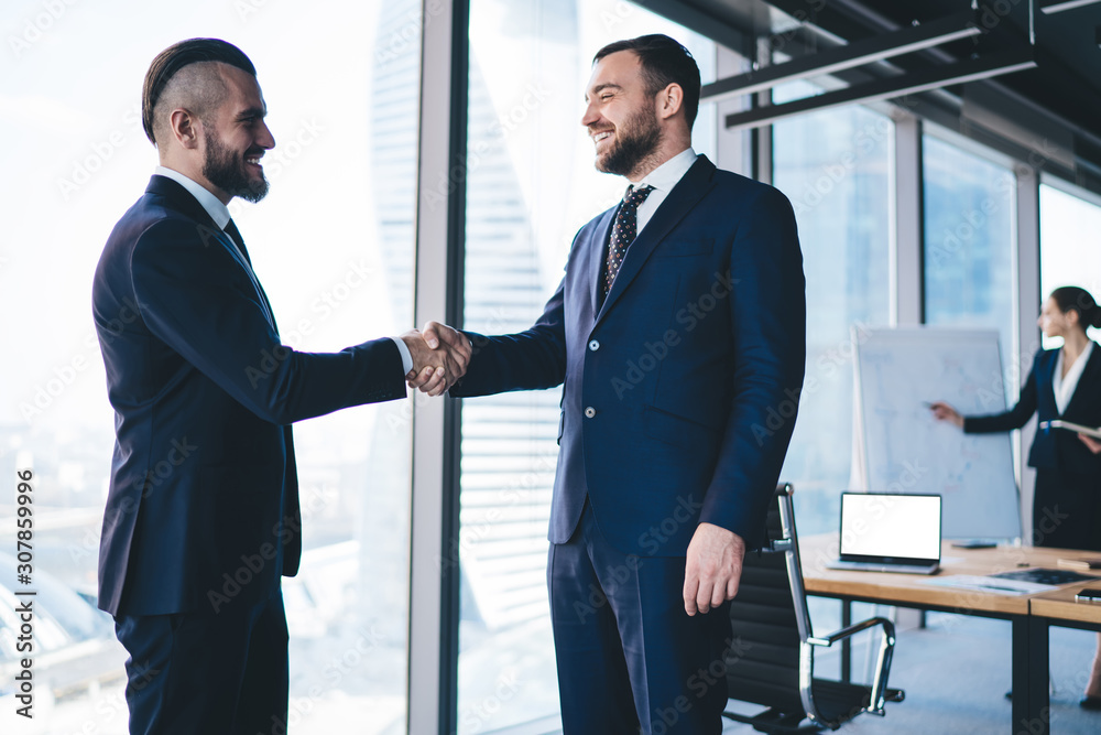 Smiling male entrepreneur shaking hand of worker