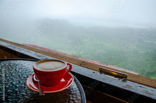 A cup of coffee on the table in a foggy morning