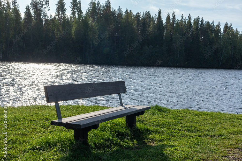 Wooden bench with great view on finish river and pine trees forest with beautiful sky landscape. Recreation area on river. Nobody. Wooden bench with great view on finish river and pine trees forest with beautiful sky landscape. Recreation area on river. Nobody.