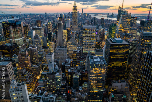 Aerial view of skyscrapers and towers in midtown skyline of Manhattan with evening sunset sky. Scenery cityscape of financial district with famous New York Landmark, illuminated Empire State Building photo