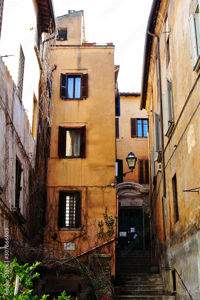 view from below on the old houses of yellow shades with shutters on the windows and narrow passages between the houses
