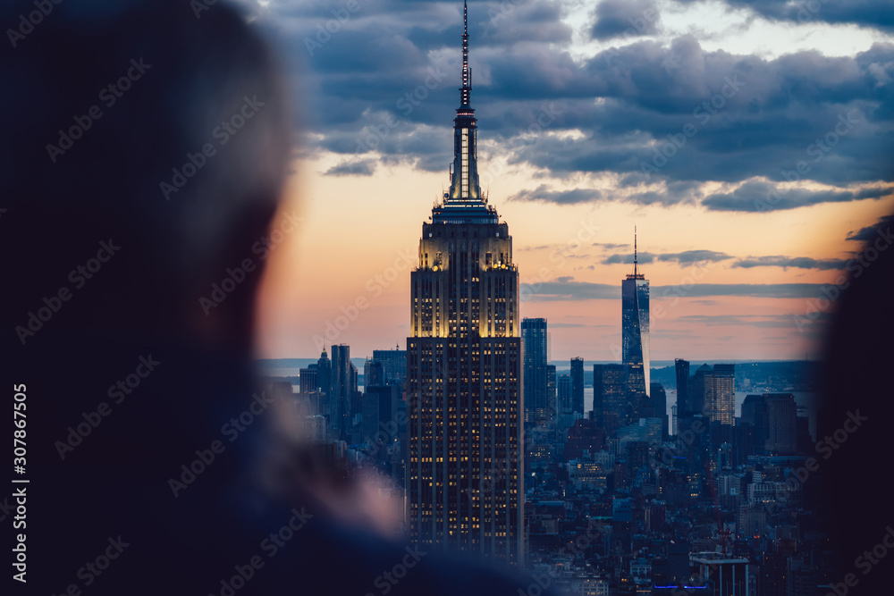 Obraz premium Aerial view of glowing skyscraper with bright buildings around located in Manhattan district of New York city. Famous landmark Empire State Building, beautiful skyline background, perfect wallpaper