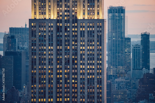 Aerial view of skyscraper building with lighted windows located in New York city at evening time. Night life of metropolis, offices and real estate. Downtown structure
