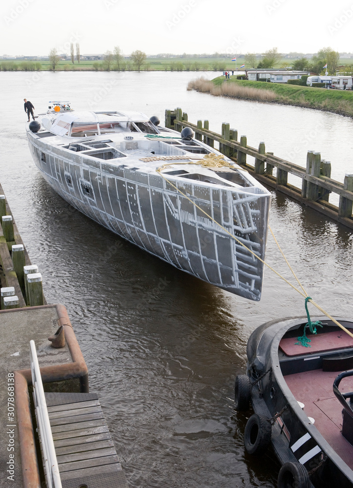 Aluminium hull. Shipbuilding industry Netherlands. Transport of super sailing yacht on the river.