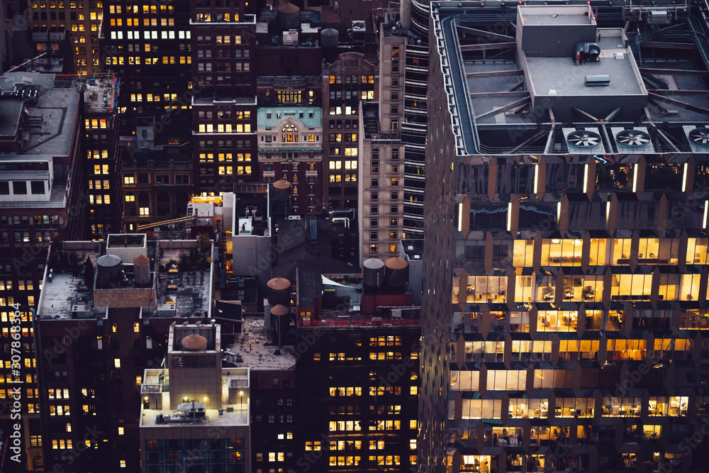 Aerial view of skyscraper building with lighted windows located in New York city at evening time. Night life of metropolis, offices and real estate. Downtown structure