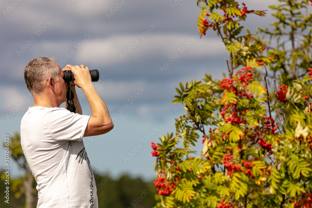 A man stands on a mountain, looks through binoculars, a beautiful sunny day A man stands on a mountain, looks through binoculars, a beautiful sunny day