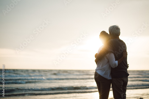 Romantic hugging couple enjoy the sunset on the beach. Back view.