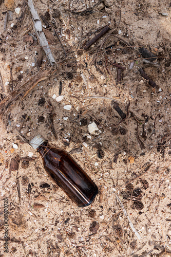 Empty used dirty glass bottles on the seaside. Ecological problem and environmental pollution. Glass bottles are non-degradable and abandoned on the coast.