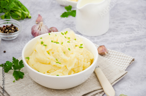Фотография Mashed potatoes with butter, milk, garlic and green onions in a bowl on a gray background
