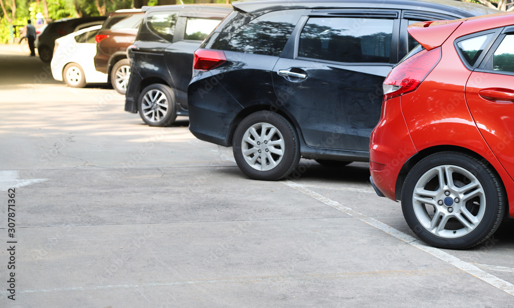 Closeup of rear, back side of red car with  other cars parking in outdoor parking area in sunny day.