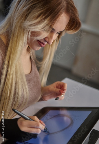 girl artist draws a digital pen on a professional tablet in her studio