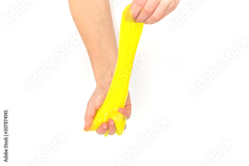 Modern toy called slime. Child playing transparent yellow slime. Hands holding a mucus isolated on a white background. Selective focus.